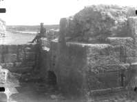 A worker with saw sitting on the ancient tower near the entrance to the citadel